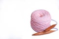A coil of large knitted yarn of peach color with 20 mm circular bamboo needles on white background, isolation, copy space