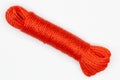 A coil of rope. Isolated. Large spool of red plastic cord on a white background. A long coil of kapron textured red cable. Durable