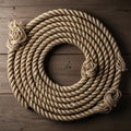 A coil of thick, twisted hemp rope arranged in a circular pattern on a dark wooden surface. The Royalty Free Stock Photo