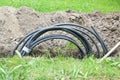 Coiled black power cable in a narrow ditch in the lawn to install a house connection, energy concept, copy space