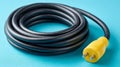 Coiled black power cord with yellow plug on blue background. Royalty Free Stock Photo