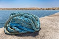 Coiled blue mooring rope at water in greek cave