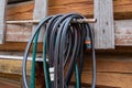 Coiled garden hose on a rusty rack against a rustic wooden wall Royalty Free Stock Photo