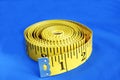 A coiled-like measuring tape isolated on blue Royalty Free Stock Photo