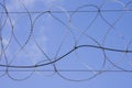 Coiled razor wire with its sharp steel barbs on top of a wire mesh perimeter fence ensuring safety and security preventing access Royalty Free Stock Photo