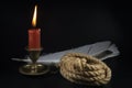 Coiled rope with burning candle and quill pen