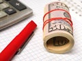 Coiling stack of dollars lies near the calculator. Close-up Royalty Free Stock Photo