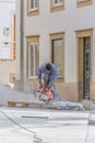 View of construction worker man cutting stone with grinder on street in Coimbra, Portugal