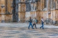 View of women tourists walking on exterior close to the Gothic exterior facade of the Monastery of Batalha, Mosteiro da Batalha,