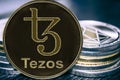 Coin cryptocurrency Tezos XTZ on the background of a stack of coins. MKR