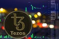 Coin cryptocurrency Tezos XTZ on night city background and chart.