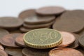 Coin of fifty euro cents on several bronze coins of five euro cents. White background Royalty Free Stock Photo