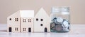 Coin in glass jar and wooden house model on table background. Business, Investment, Money Saving, Real Estate and Retirement plan