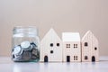 Coin in glass jar and wooden house model on table background. Business, Investment, Money Saving, Real Estate and Retirement plan