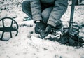 The coin is a lucky find with a metal detector in the field. Silhouette of a man during a treasure hunt in winter on a snowy field