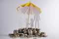 Coin stacks with family with the protect umbrella on dark background