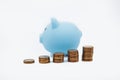 Coin tower and blue piggy bank on white background. Money saving concept Royalty Free Stock Photo