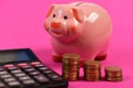 Coin tower, calculator and piggy bank on pink background Royalty Free Stock Photo