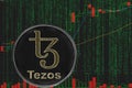 Coin XTZ Tezos cryptocurrency on the background of binary crypto matrix text and price chart.