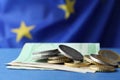 Coins and banknotes on blue table against European Union flag, closeup. Space for text Royalty Free Stock Photo