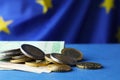 Coins and banknotes on blue table against European Union flag, closeup. Space for text Royalty Free Stock Photo