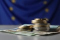 Coins and banknotes on table against European Union flag. Space for text Royalty Free Stock Photo