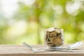 Coins in clear money jar, fork and spoon on wooden table with green blur light background. Savings money for eating concept