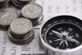 Coins, compass and business section of newspaper for exchange rate and direction on stock market for investor