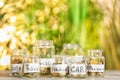 Coins for different needs in glass jars on table outdoors. Money savings concept Royalty Free Stock Photo