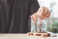 Coins in a glass bottle, Hand of male or female putting coins in jar with money stack step growing growth saving money on nature Royalty Free Stock Photo