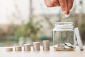 Coins in a glass bottle, Hand of male or female putting coins in jar with money stack step growing growth saving money on nature Royalty Free Stock Photo