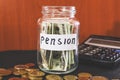 Coins in a glass jar and a calculator on black. Saving money. Pension concept.