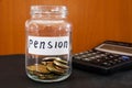 Coins in a glass jar and a calculator on black. Saving money. Pension concept.