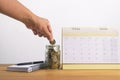 Coins in glass jar and calendar on wooden table for saving,accou