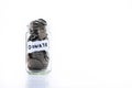 Coins in glass jar with a note written ` DONATE `. on a white background.