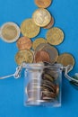 Coins in a glass jar, scattered change currency money on a blue background. a place for text. Concept: financial crisis, decrease