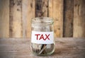 Coins in glass money jar with tax label, financial concept. Royalty Free Stock Photo