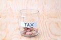 Coins in glass money jar with tax label, financial concept. Vintage wooden background Royalty Free Stock Photo