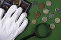 Coins on a green cloth, white gloves and a magnifying glass, top view Royalty Free Stock Photo