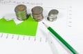 Coins on green graphs and charts background with pencil. money a Royalty Free Stock Photo