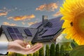 Money on hand against a house with solar panels installed on the roof. Economic benefits of renewable energy. Conceptual image Royalty Free Stock Photo