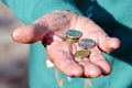 The coins are in the hands of the old lady. An elderly woman with money in her hands. Poverty alms