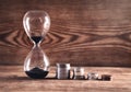 Coins and hourglass on a wooden background Royalty Free Stock Photo