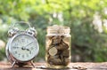 Coins in jar with alarm clock on nature background, Concept finance business, saving investment and accounting concept. Royalty Free Stock Photo