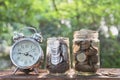 Coins in jar with alarm clock on nature background, Concept finance business, saving investment and accounting concept. Royalty Free Stock Photo