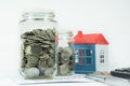 Coins, Jar and House in the background Royalty Free Stock Photo