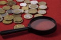 Coins and a magnifying cloth on a red cloth close-up