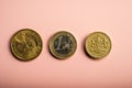 Coins one dollar, one euro, one pound on a pink background.