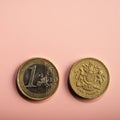 Coins one euro, one pound on a pink background.