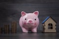 coins and a piggy bank next to the house Royalty Free Stock Photo
